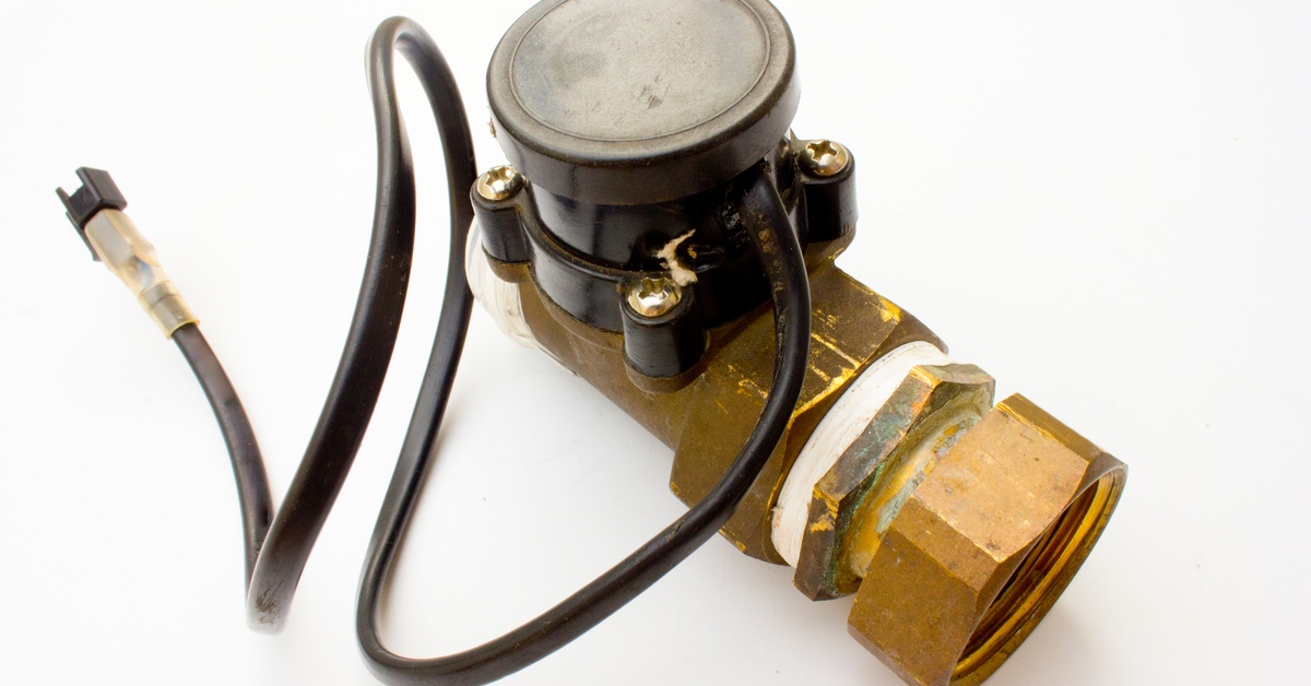 A brass solenoid valve with a black electrical component and cable, isolated on a white background.