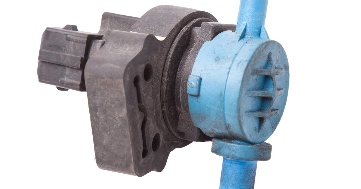 A solenoid valve with blue tube connections and gray components sits by itself on top of a white background.