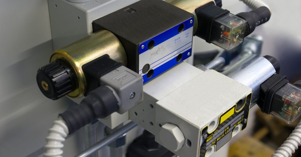 An industrial valve with a metal body with attached wires and visible connectors against a plain background.