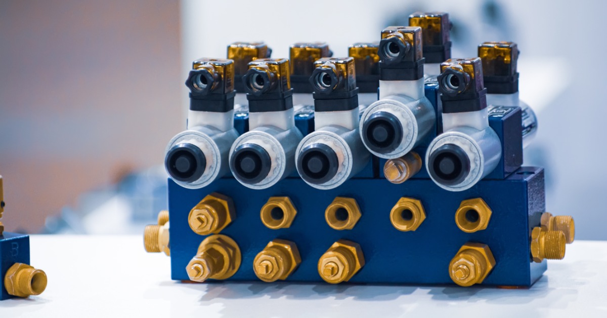 A hydraulic distributor block with multiple solenoid valves mounted in a row, showing metal fittings and ports.