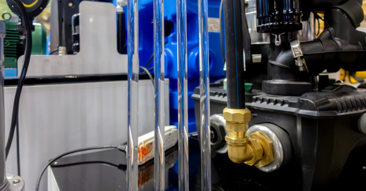 Industrial fluid control valves connect to metal tubing, gauges, and fittings on an indoor machinery panel.