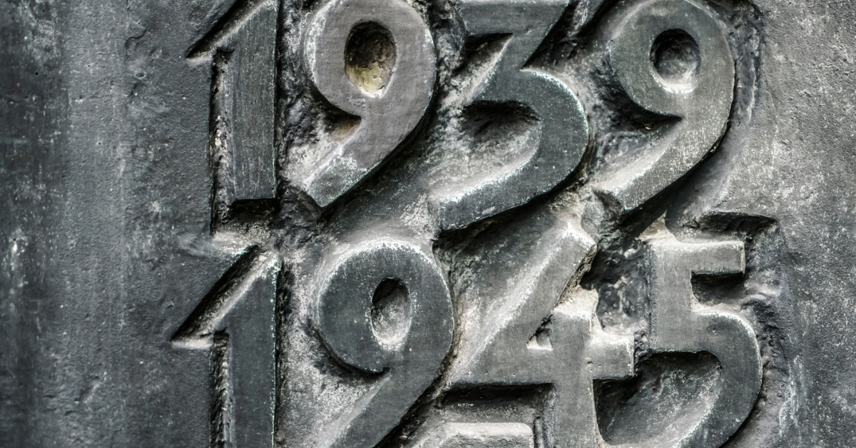 The numbers 1939 and 1945 are carved into a pale stone memorial wall with a detailed, textured surface.