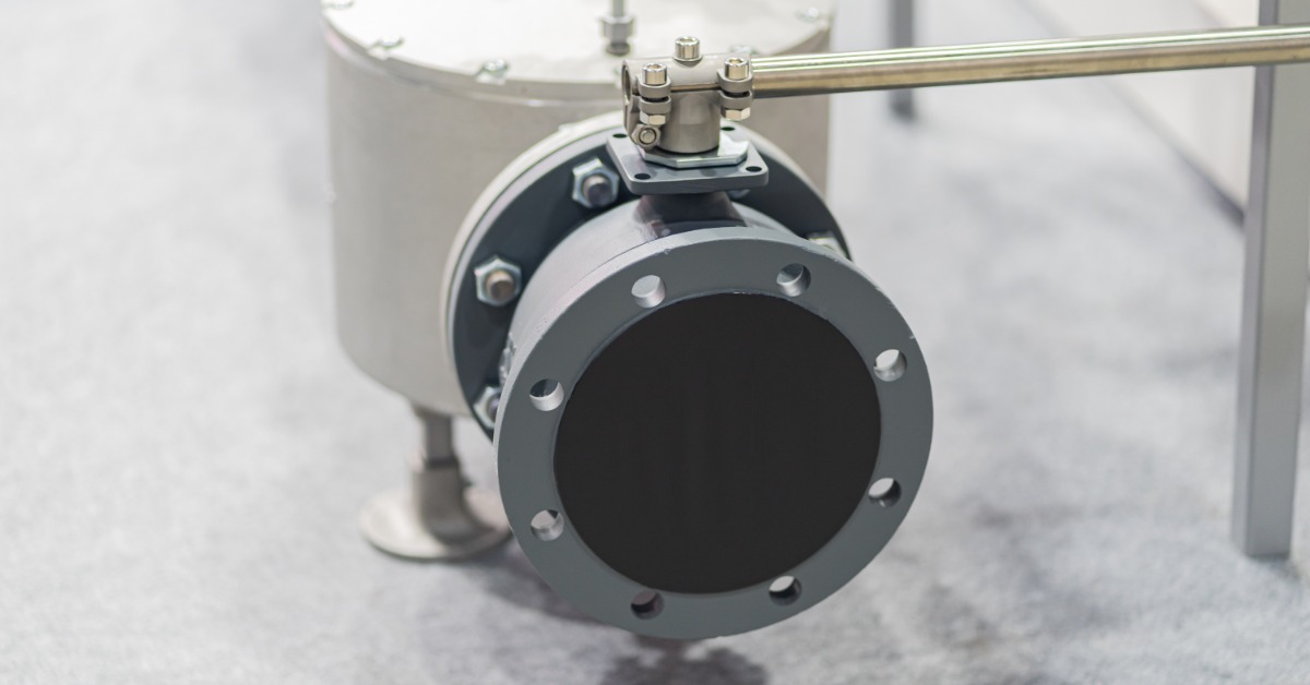 A close-up of a solenoid valve installation with electrical wiring and metal fittings attached to industrial piping.