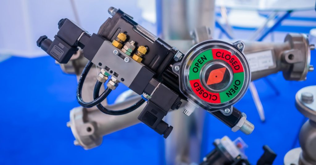 A close-up of an electric solenoid valve mounted on industrial equipment, with wiring and metal components.